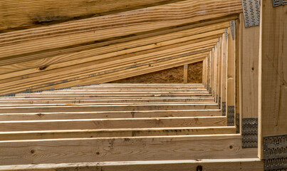 Roofing support trusses arranged as a triangulated system of straight interconnected lumber pieces. These structural elements are newly installed.