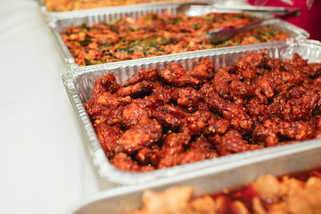 Spicy Korean fried chicken and sides in catering trays with copy space 