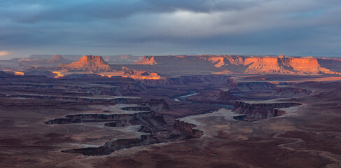 Naklejka premium Sunrise near the Green River overlook in the Island in the Sky district of Canyonlands National Park, Utah. The White Rim 4x4 road can be seen on the bench below. 