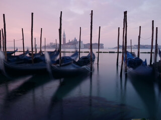 Long exposure photo of Gondolas moored near San Marco square at sunrise with a view at San Giorgio...