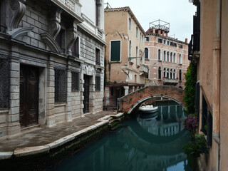 Long exposure photo of canal in Venice with arc bridge and moored boat. Venice, Italy.