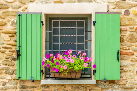 Brisighella, Emilia Romagna, Italy. Colorful flower basket in a shuttered window of a stone house.