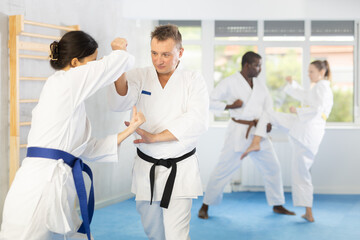 Obraz premium Woman and man in kimono sparring together in gym during karate training
