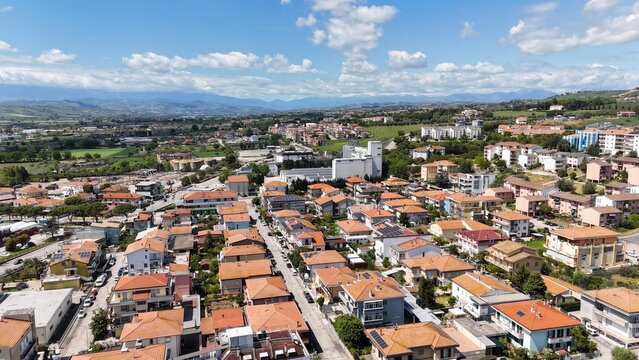 This is an aerial view of a residential area in an Italian town, possibly Roseto degli Abruzzi, featuring houses with red-tiled roofs and winding streets.