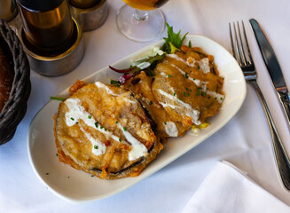 Tasty sliced aubergine in crispy batter served with yogurt sauce