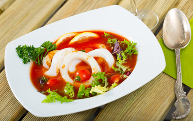 Dish of Mediterranean cuisine - tomato soup with squid and greens