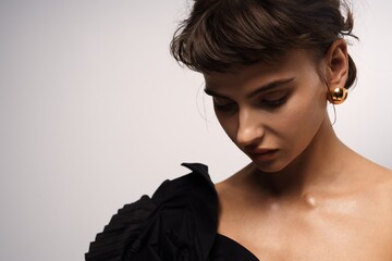 Portrait of a woman in a black dress with elegant earrings, showcasing soft lighting and a thoughtful expression