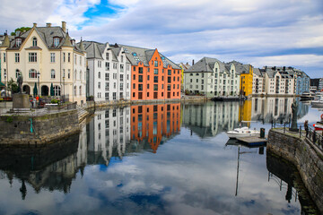 Alesund, Norway. Canal with colorful painted houses, boats, marina, sailor statue.