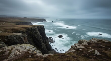 Fototapeta premium A captivating coastal view with dramatic cliffs, waves, and an expansive ocean under a cloudy sky.