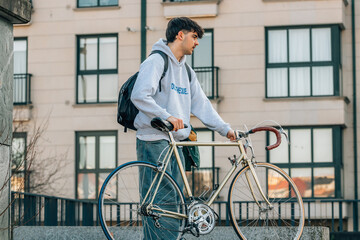 young man walking on the street with vintage bicycle
