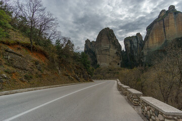 Country road at the landscape of the famous and majestic rock formations of Meteora under a cloudy sky, Kalambaka, Thessaly, Greece