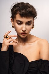 Woman poses gracefully showcasing elegant jewelry against a neutral background in a studio setting