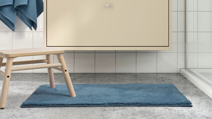 Soft blue bath mat and wooden stool in modern bathroom with light tile and storage cabinet.