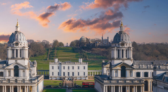 The Old Royal Naval College's twin domes, Queen's House, Greenwich Park hill, and Royal Observatory with a red bus in the foreground in London.