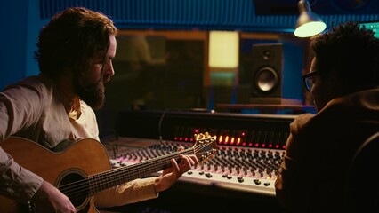 Songwriter composing a song with sound engineer in professional studio, recording session with his...
