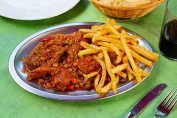 Tasty stewed with peas asturian beef with french fries served at plate