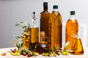 Bottles and carafes with olive oil and fresh olives on wooden table. Ingredients for cooking