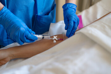 Nurse injecting medicine into patient's arm through iv catheter