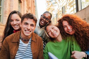Joyful group of diverse young friends posing together for a fun portrait while sharing laughter and...