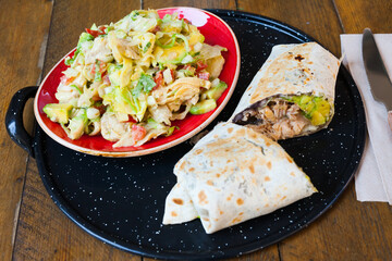 Mexican cuisine. Chicken salad with avocado and burrito with tuna