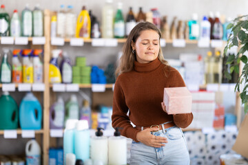 Young girl experiencing pain choosing feminine pads in large supermarket