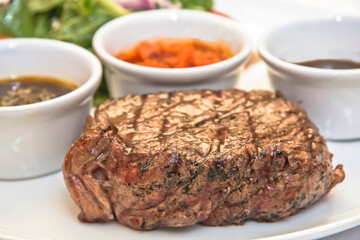 Grilled beef steak with lettuce salad and spicy sauces, plate of sliced ​​roast beef with salad and tomato on a white background