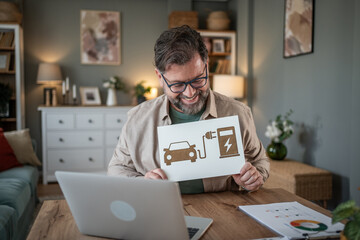 Businessman showing electric vehicle charging station sign during video conference