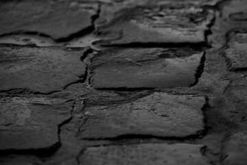 close-up of wet dark gray cobblestones with little puddles, moody rain