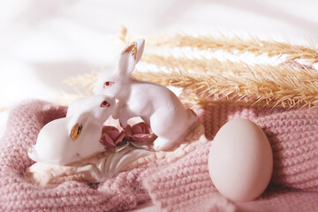 Easter home decorations, couple rabbits and fresh flowers. Easter still life. Sunlight and pastel colors