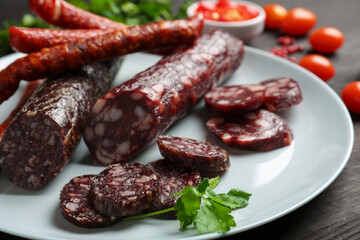Different smoked sausages, cherry tomatoes and spices on table, closeup