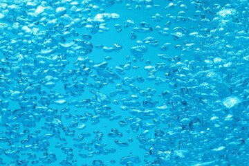 Many water bubbles on blue background, closeup