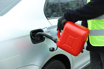 Man with canister refueling car outdoors, closeup
