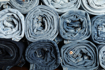 Different stylish rolled jeans as background, top view