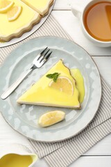 Delicious cheesecake with lemon curd served on white wooden table, flat lay