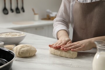 Making pretzels. Woman shaping dough at table in kitchen, closeup