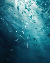 Underwater view of sunlight filtering through ocean water, teeming with fish and leaves.