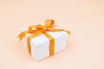 Obraz premium white gift box with an orange ribbon tied around it