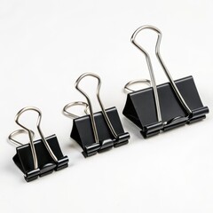 Three black binder clips of varying sizes arranged together on a white background.