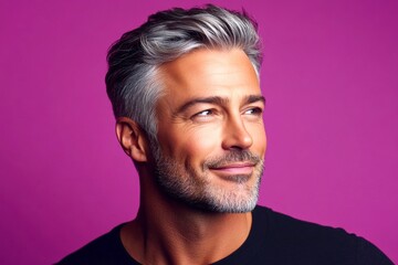 Fototapeta premium A peaceful and radiant male in a confident pose. Fashionable men's high and tight haircut - midlife white man with grey hair. Purple solid background. Visual idea of style for aging men.