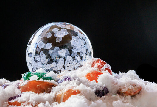 USA, Indiana, Carmel. Frozen soap bubble and polished stones in snow.