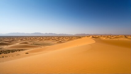 Endless Golden Waves: A Serene Desert Landscape Under a Clear Blue Sky Stretching Towards Distant Mountain Ridges.
