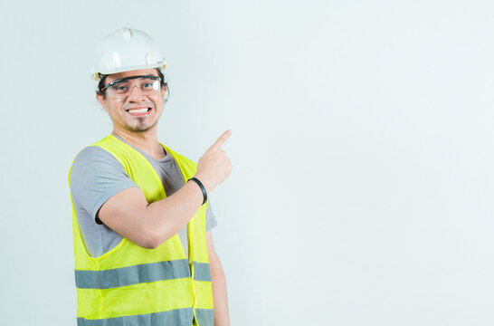 Happy male builder pointing to side isolated. Smiling male construction worker pointing blank space