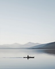 A man is paddling a kayak on a lake surrounded by mountains