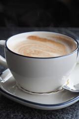 Steaming coffee cup with swirling pattern on a dark surface