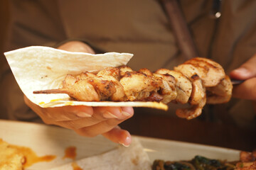 Grilled chicken skewer being served with flatbread at local eatery