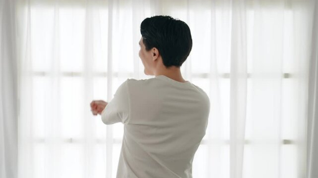 窓際で爽やかにストレッチする男性