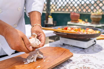 Chef peeling garlic for paella on rooftop terrace