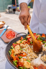 Chef preparing delicious paella outdoors with fresh ingredients