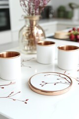 White ceramic cups with copper rims and a decorative coaster