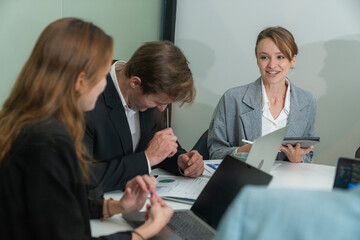 Team members engaged in a collaborative meeting discussing projects in a modern office setting